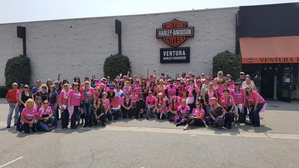 Huge group of riders in pink posing outside Ventura Harley-Davidson